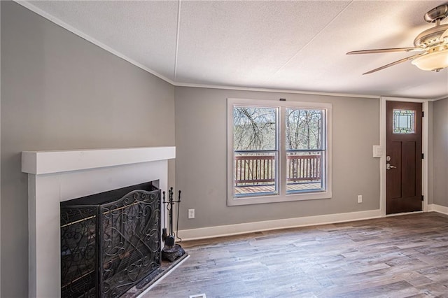 unfurnished living room with a fireplace, a textured ceiling, baseboards, and wood finished floors