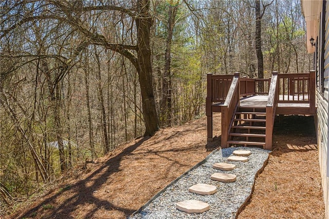 view of yard featuring stairs, a view of trees, and a wooden deck