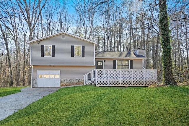 split level home with driveway, a garage, stone siding, a chimney, and a front yard