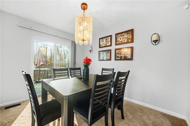 carpeted dining room featuring a chandelier, visible vents, and baseboards