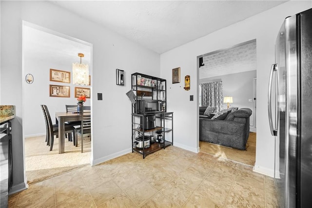 interior space with a textured ceiling, a chandelier, and baseboards