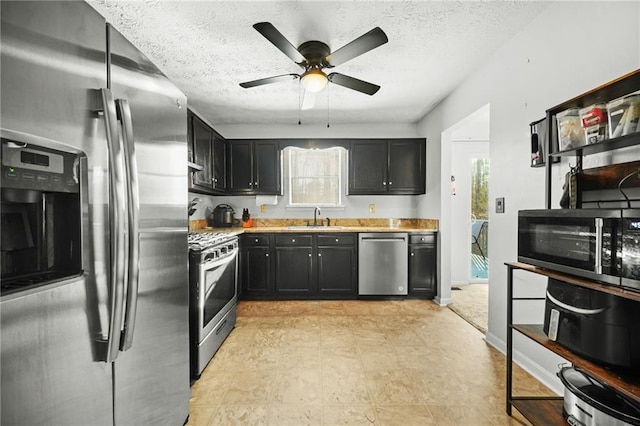 kitchen with light countertops, appliances with stainless steel finishes, a sink, and dark cabinetry