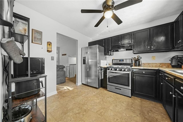 kitchen with under cabinet range hood, appliances with stainless steel finishes, and dark cabinets