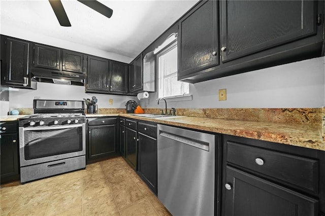 kitchen featuring under cabinet range hood, stainless steel appliances, a sink, a ceiling fan, and dark cabinetry