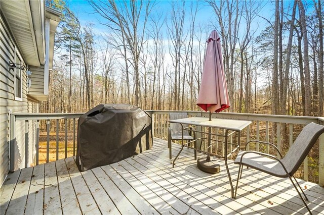 wooden terrace featuring outdoor dining area and a grill