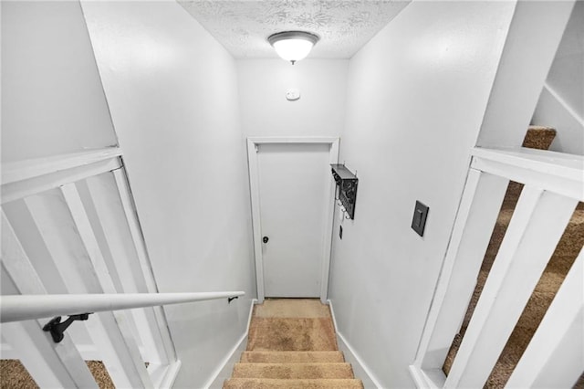 staircase featuring a textured ceiling