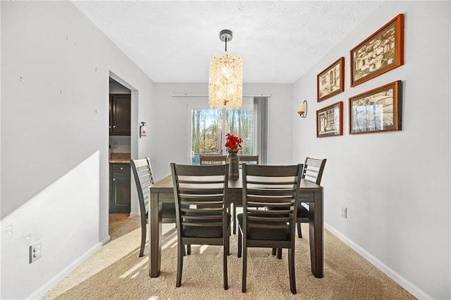 dining space with light colored carpet, a notable chandelier, a textured ceiling, and baseboards