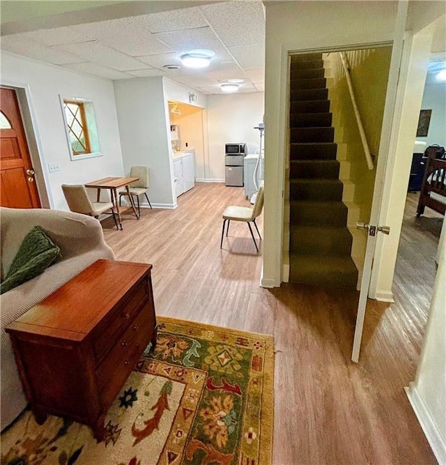 interior space with a paneled ceiling and light hardwood / wood-style floors