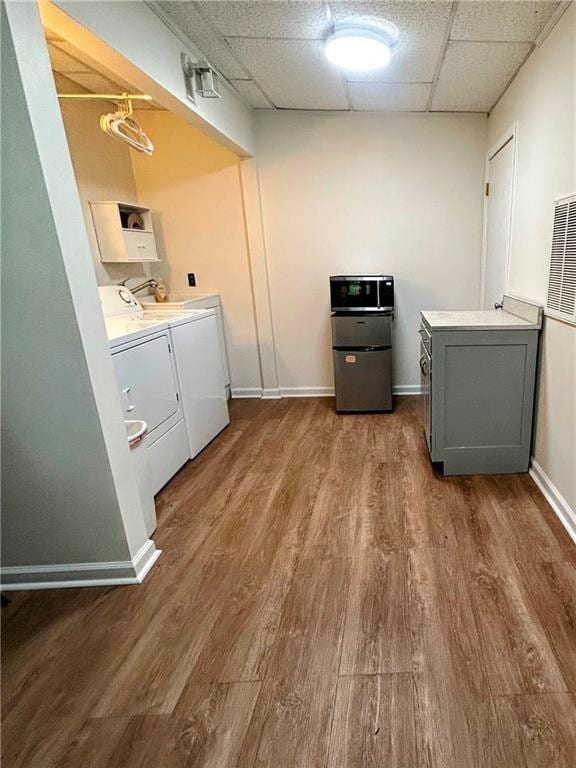 laundry area featuring wood-type flooring, cabinets, and washer and clothes dryer