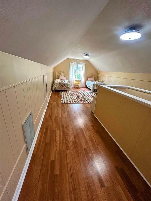 bonus room featuring lofted ceiling, wood walls, dark hardwood / wood-style flooring, and a textured ceiling