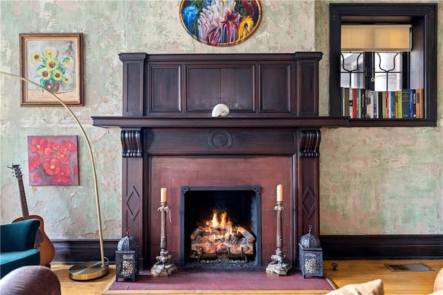 interior details with wood finished floors, a fireplace with flush hearth, baseboards, visible vents, and wallpapered walls