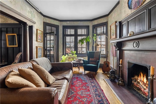 sitting room with dark wood-style floors, ornamental molding, and a brick fireplace