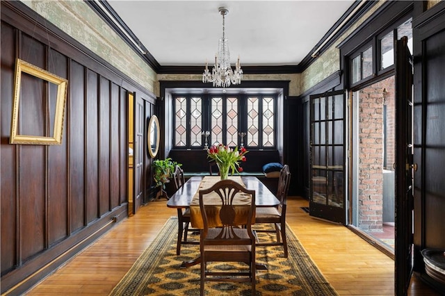 dining area with an inviting chandelier, light wood finished floors, and crown molding