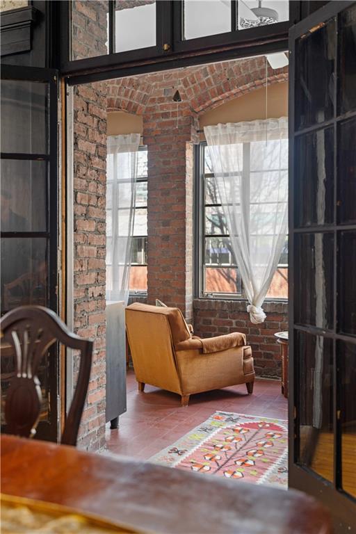 sitting room with tile patterned flooring and brick wall