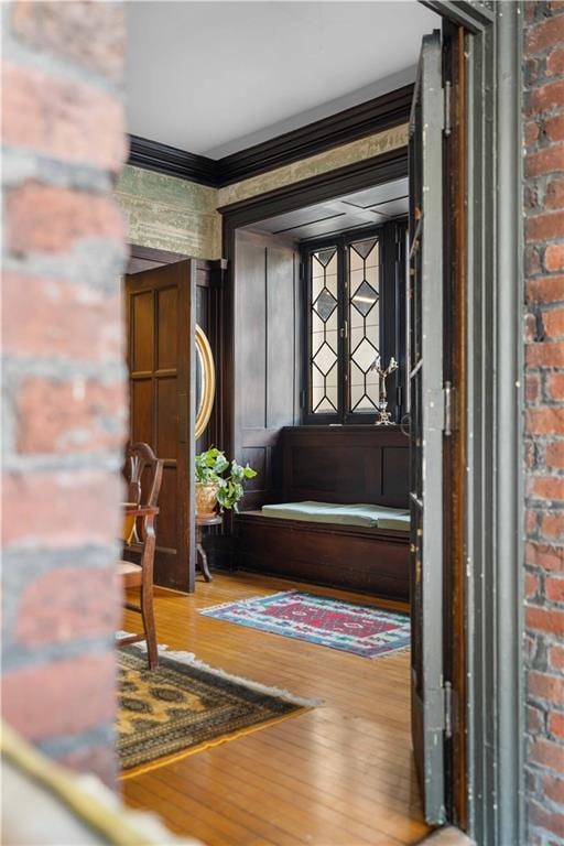 interior space featuring brick wall, ornamental molding, and wood finished floors