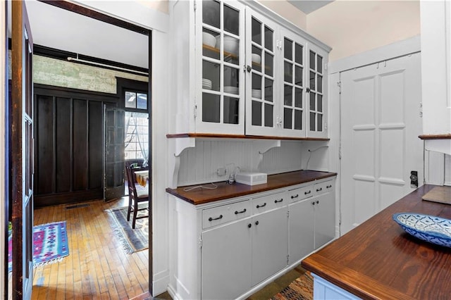 kitchen featuring glass insert cabinets, dark countertops, white cabinetry, and dark wood-type flooring