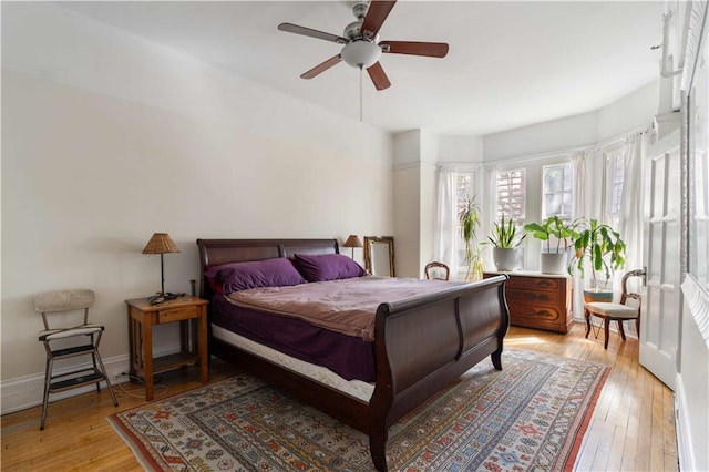 bedroom featuring light wood-type flooring, a ceiling fan, and baseboards