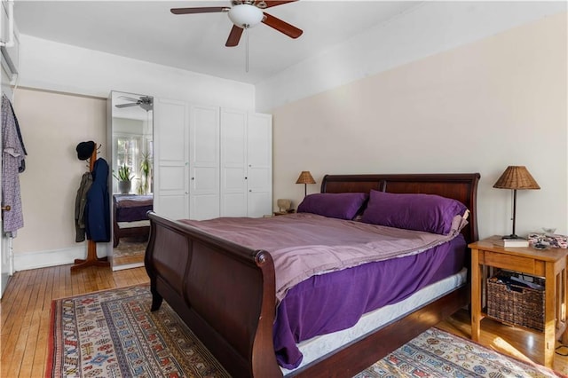 bedroom featuring a closet, dark wood finished floors, a ceiling fan, and baseboards