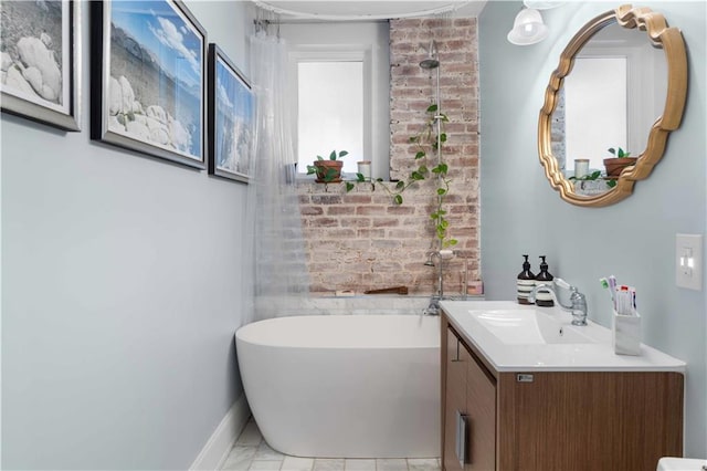 bathroom with brick wall, marble finish floor, a freestanding tub, and vanity