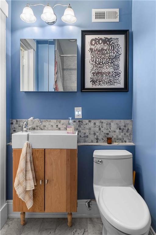 bathroom featuring toilet, marble finish floor, vanity, and visible vents