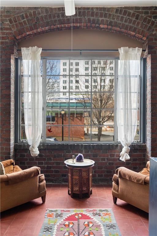 sitting room featuring tile patterned flooring and brick wall