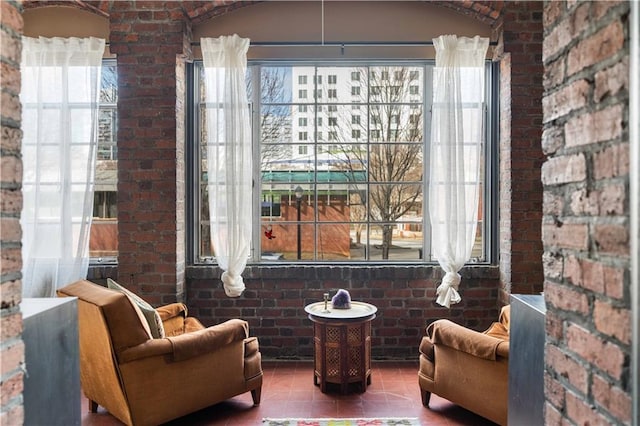 sitting room featuring tile patterned flooring, plenty of natural light, and brick wall