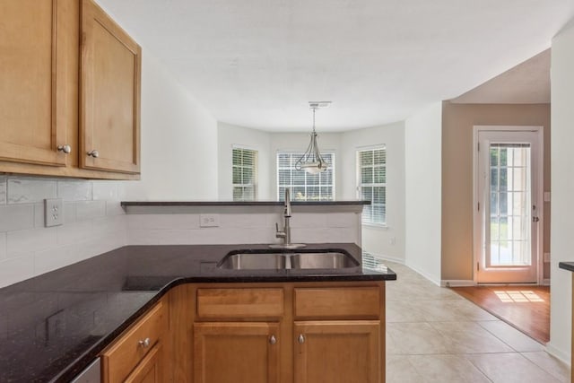 2410 Napa Valley Dr, Villa Rica, GA 30180 - kitchen with a peninsula, tasteful backsplash, dark stone countertops, light tile patterned flooring, and hanging light fixtures