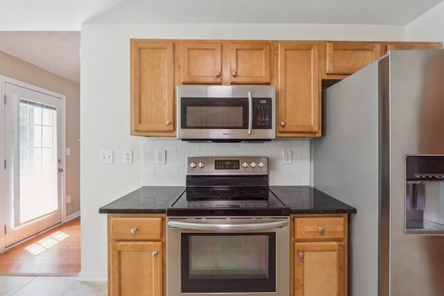 2410 Napa Valley Dr, Villa Rica, GA 30180 - kitchen featuring stainless steel appliances, tasteful backsplash, dark stone counters, and brown cabinetry