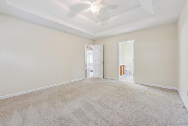 2410 Napa Valley Dr, Villa Rica, GA 30180 - unfurnished bedroom featuring a tray ceiling, light colored carpet, ensuite bathroom, and a ceiling fan