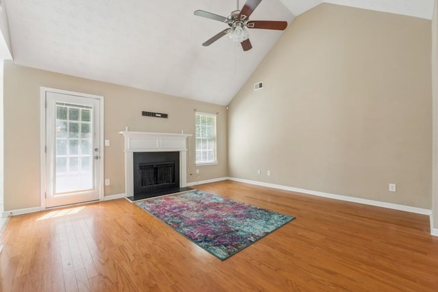 2410 Napa Valley Dr, Villa Rica, GA 30180 - unfurnished living room with ceiling fan, healthy amount of natural light, light wood finished floors, high vaulted ceiling, and a fireplace with flush hearth