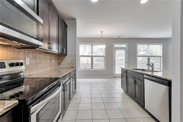 kitchen with sink, light stone countertops, stainless steel appliances, and a wealth of natural light