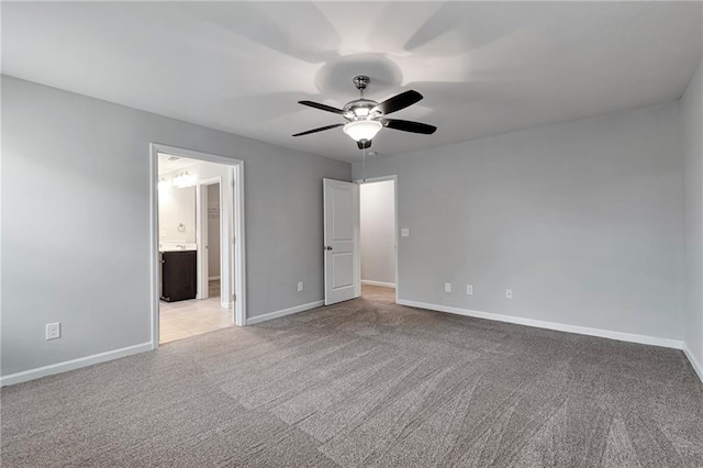 unfurnished bedroom with ceiling fan, ensuite bathroom, and light carpet