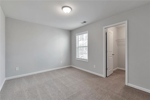 unfurnished bedroom with light carpet, a walk in closet, and a closet