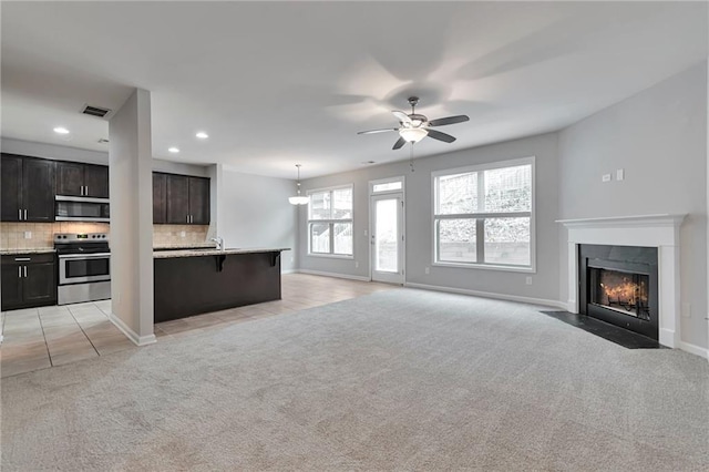 unfurnished living room with light carpet, ceiling fan, and sink