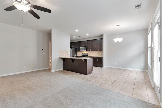 kitchen with a kitchen breakfast bar, tasteful backsplash, kitchen peninsula, light carpet, and dark brown cabinets