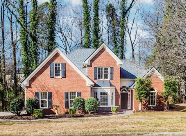 traditional-style house with a front yard, brick siding, and roof with shingles