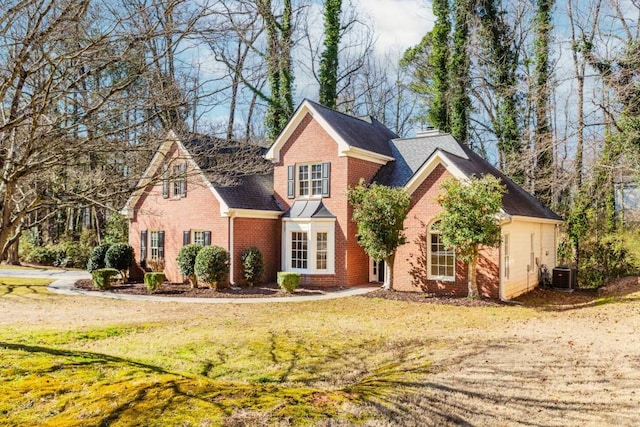 traditional-style home with central AC, brick siding, a chimney, and a front yard