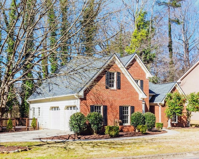 traditional-style home featuring roof with shingles, a front lawn, concrete driveway, and brick siding