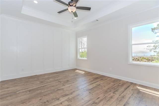 spare room with ceiling fan, visible vents, wood finished floors, and a raised ceiling