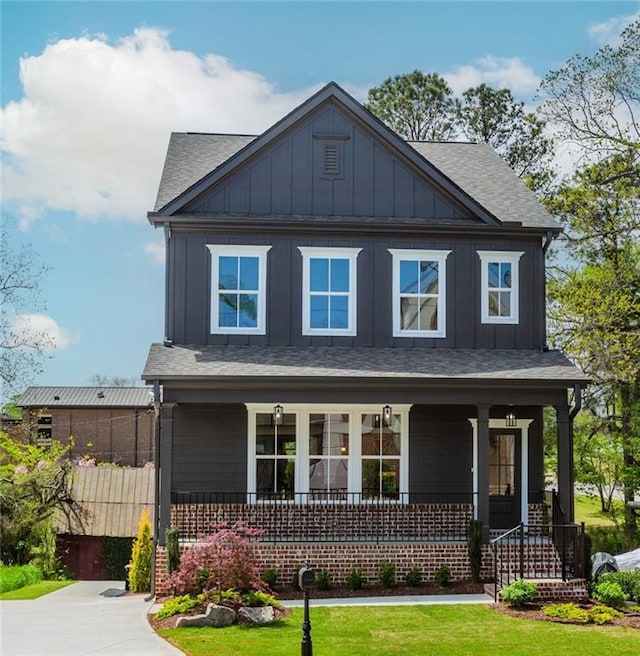 craftsman inspired home with a porch, a shingled roof, board and batten siding, and a front yard