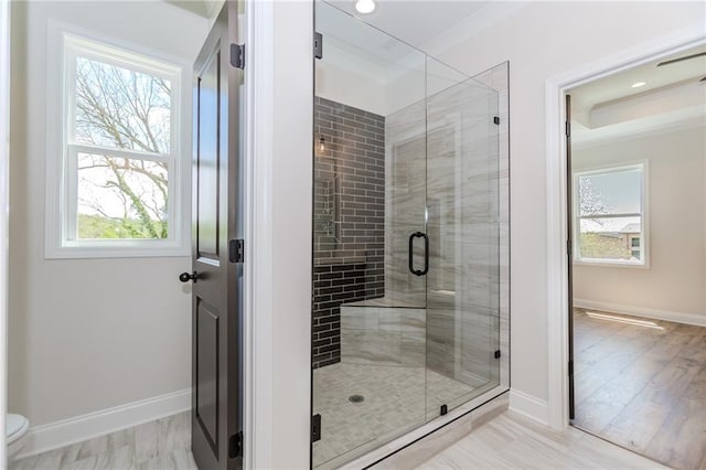 full bath featuring baseboards, ornamental molding, a shower stall, and a wealth of natural light