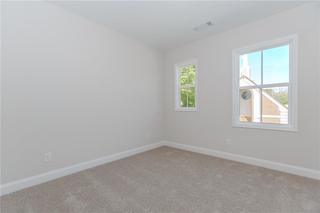 empty room featuring baseboards, visible vents, and light colored carpet