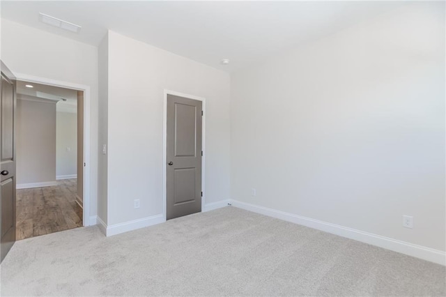 empty room featuring visible vents, carpet, and baseboards