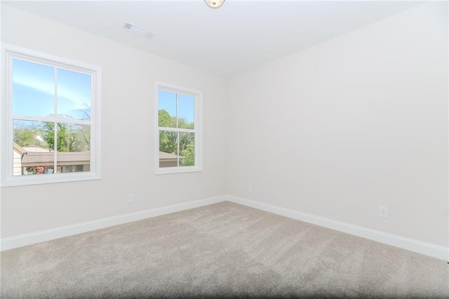 spare room with baseboards, carpet, and visible vents