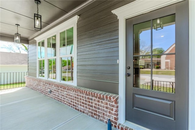 entrance to property with a porch and brick siding