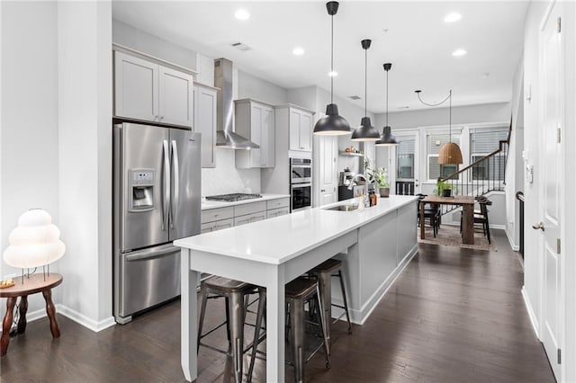 kitchen with appliances with stainless steel finishes, backsplash, wall chimney exhaust hood, sink, and decorative light fixtures