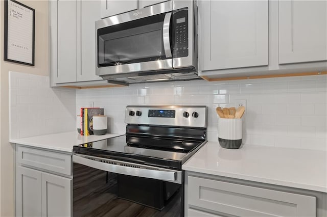 kitchen featuring appliances with stainless steel finishes, tasteful backsplash, and light countertops
