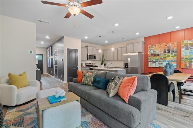 living area with light wood-style flooring, a ceiling fan, recessed lighting, and baseboards