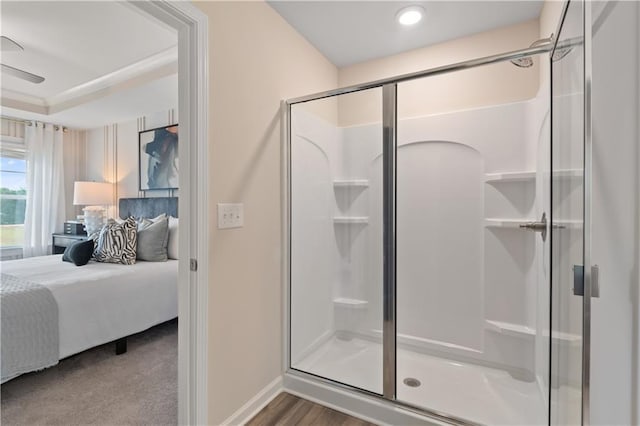 ensuite bathroom with baseboards, a shower stall, and wood finished floors