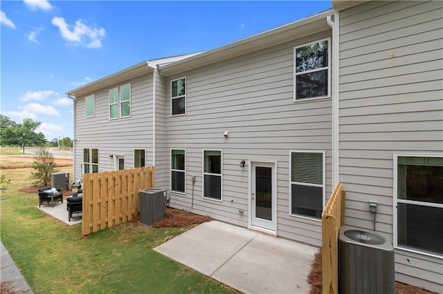 rear view of house with cooling unit, a patio, and a lawn